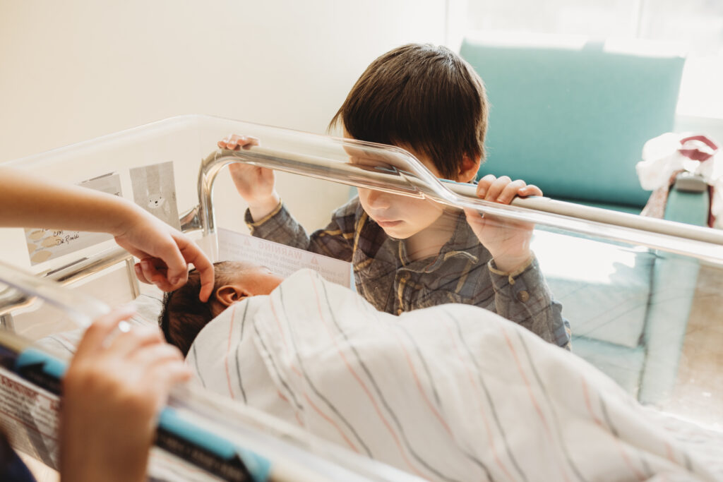 older siblings meeting new sibling in the hospital room after birth, baby laying in bassinet
fresh 48 photography