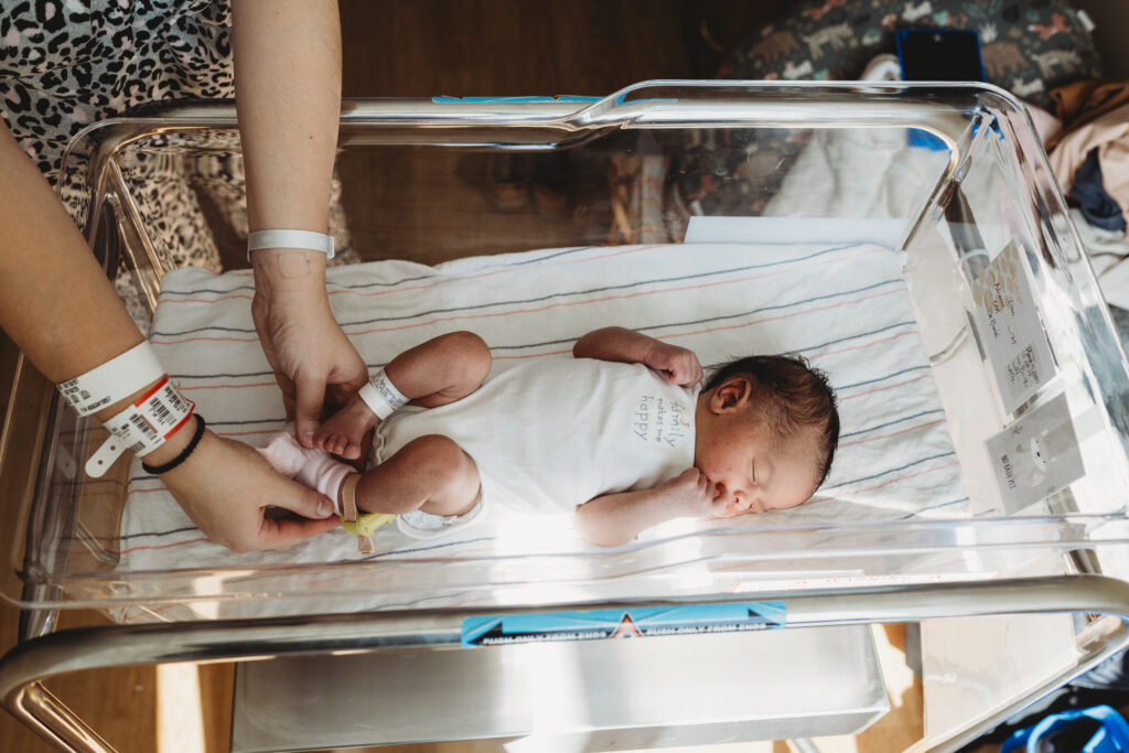Newborn baby resting in hospital bassinet during Fresh 48 newborn photo session