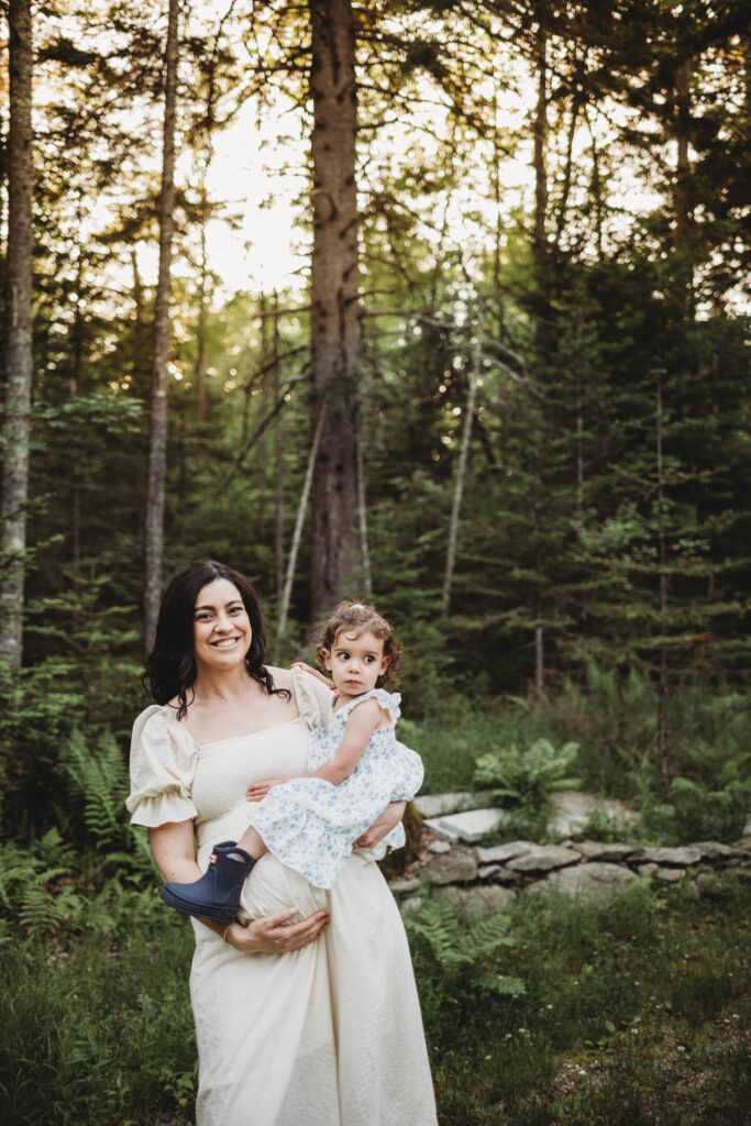 Blue Hill maternity photographer capturing family along wooded path by cottage