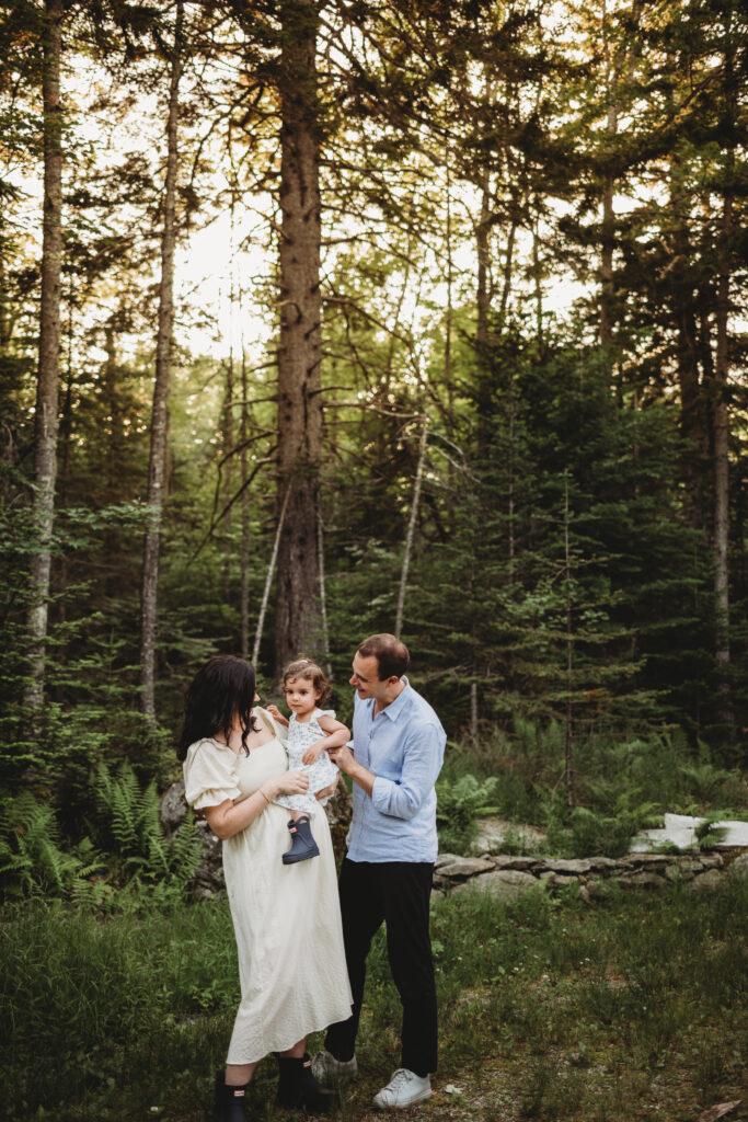 Blue Hill maternity photographer capturing family along wooded path by cottage