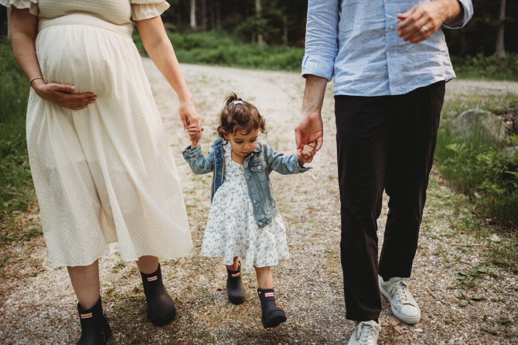 Blue Hill maternity photographer capturing family along wooded path by cottage