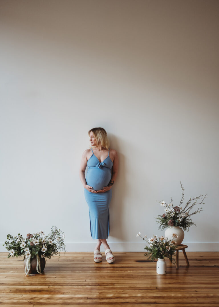 pregnant mother leaning against the wall in studio mini session at Franklin Haus Studio