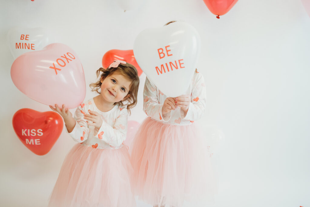 Children celebrating Valentine’s Day with balloons and confetti during family photo session