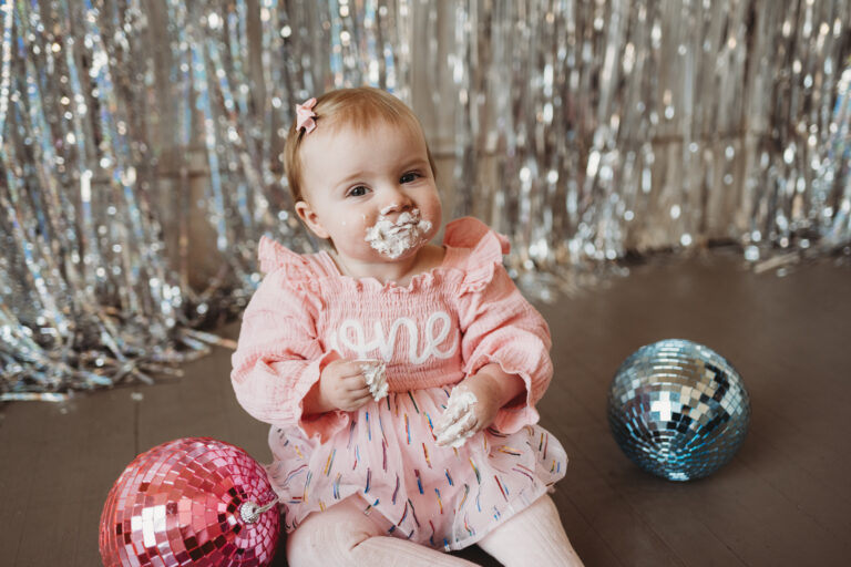 child with cake on their face taking cake smash photos for first birthday