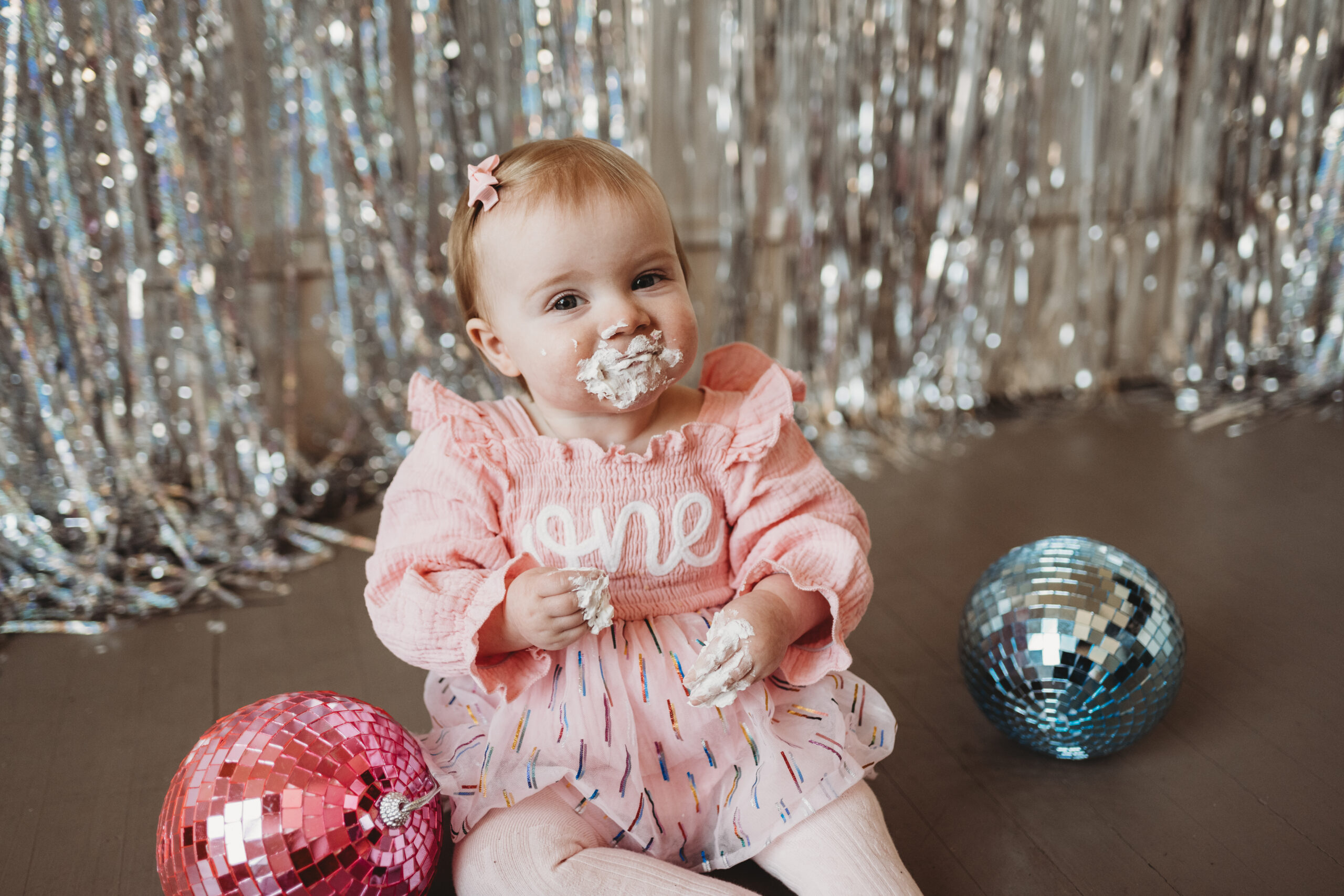 child with cake on their face taking cake smash photos for first birthday